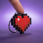 Dedo presionando el llavero corazon pixel clicker, mecanismo rigido tipo tecla