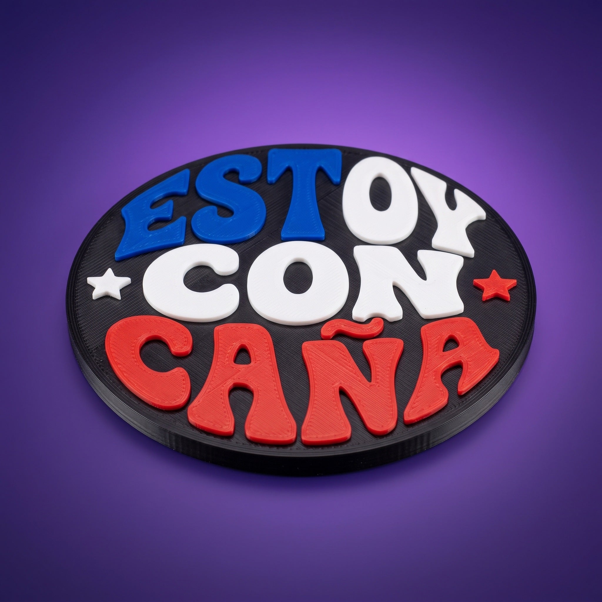 Posavasos impreso en 3D con la frase Estoy con Caña en azul, blanco y rojo sobre disco negro
