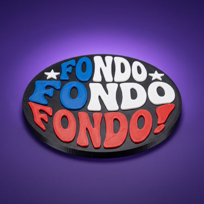 Posavasos impreso en 3D con la frase Fondo Fondo Fondo en azul, blanco y rojo sobre disco negro